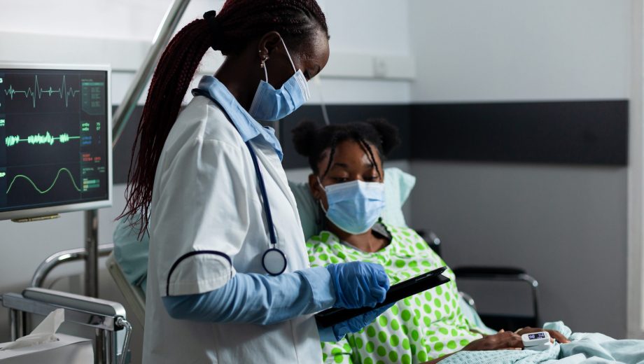 Medic of african ethnicity helping sick patient at clinic