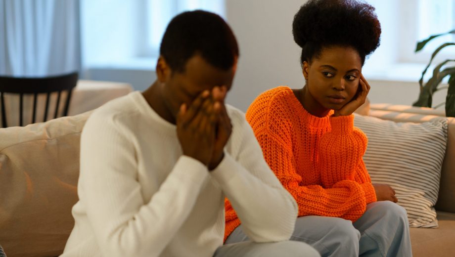 Misunderstandings in love relationships. Sad african family couple sitting on sofa after conflict