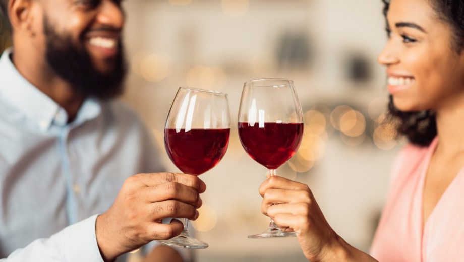 Smiling black woman and man drinking red wine